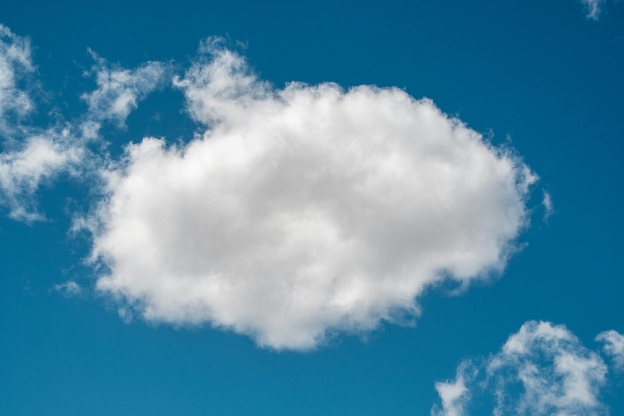 A bright, puffy cloud isolated in a clear blue sky, perfect for backgrounds or peaceful themes.