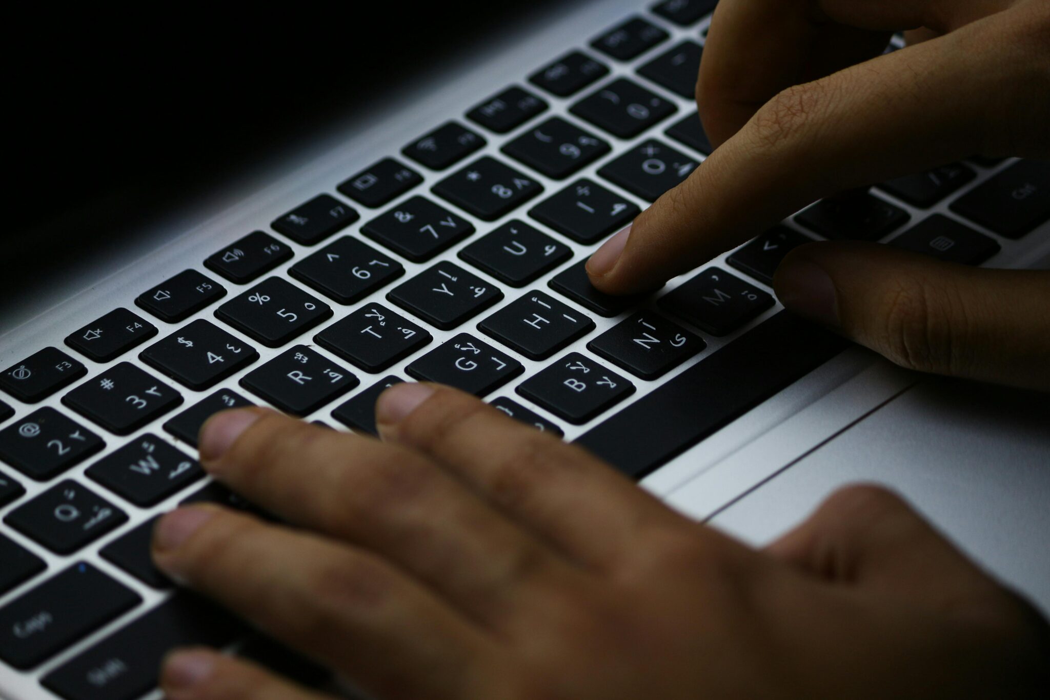 Focused typing on a laptop's illuminated keyboard, enhancing productivity in a digital workspace.